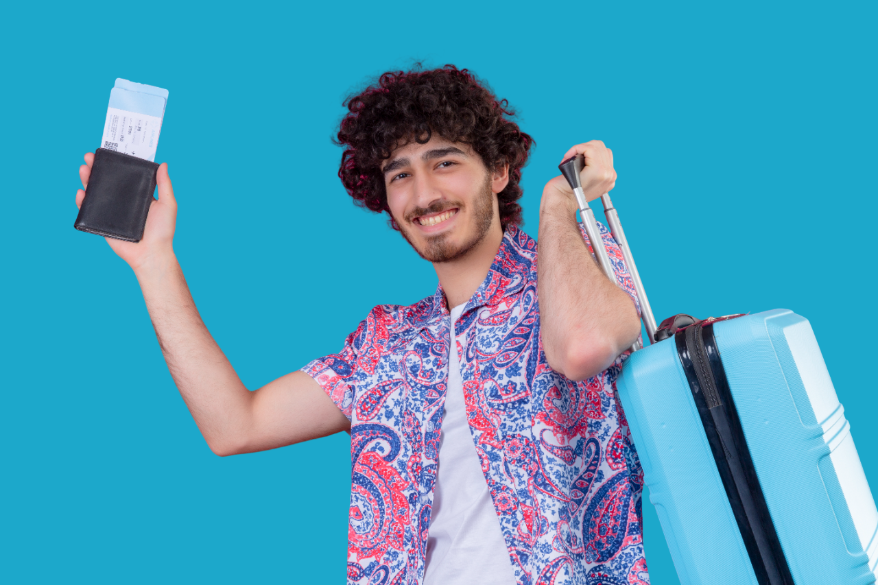 smiling young handsome curly traveler man holding wallet airplane tickets suitcase isolated pink wall Photoroom 1